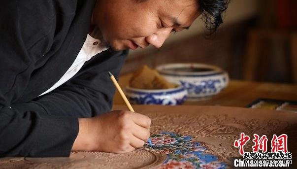 图为贾宏伟为皮画上色。　受访者供图 摄